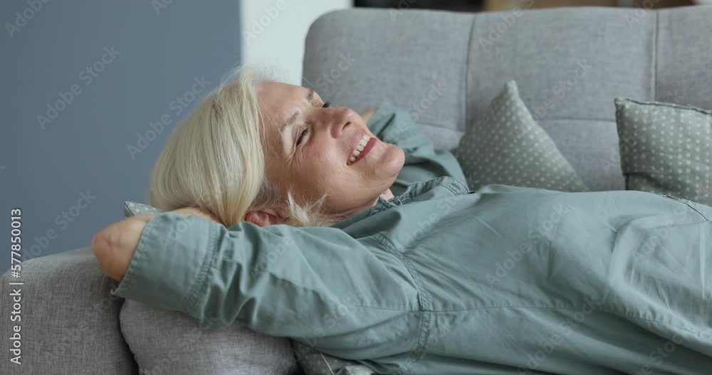 Close up elderly woman take daytime nap lying on cozy soft sofa cushions, closes her eyes, breathing fresh clean air inside warm or cool living room with climate control and air-condition. Relaxation Close up elderly woman take daytime nap lying on cozy soft sofa cushions, closes her eyes, breathing fresh clean air inside warm or cool living room with climate control and air-condition. Relaxation