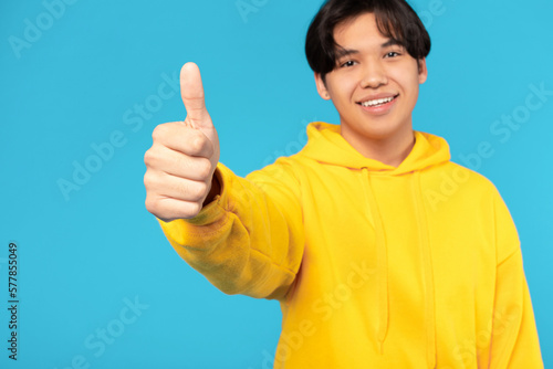 Korean Teenager Boy Gesturing Like Approving Offer On Blue Background © Prostock-studio