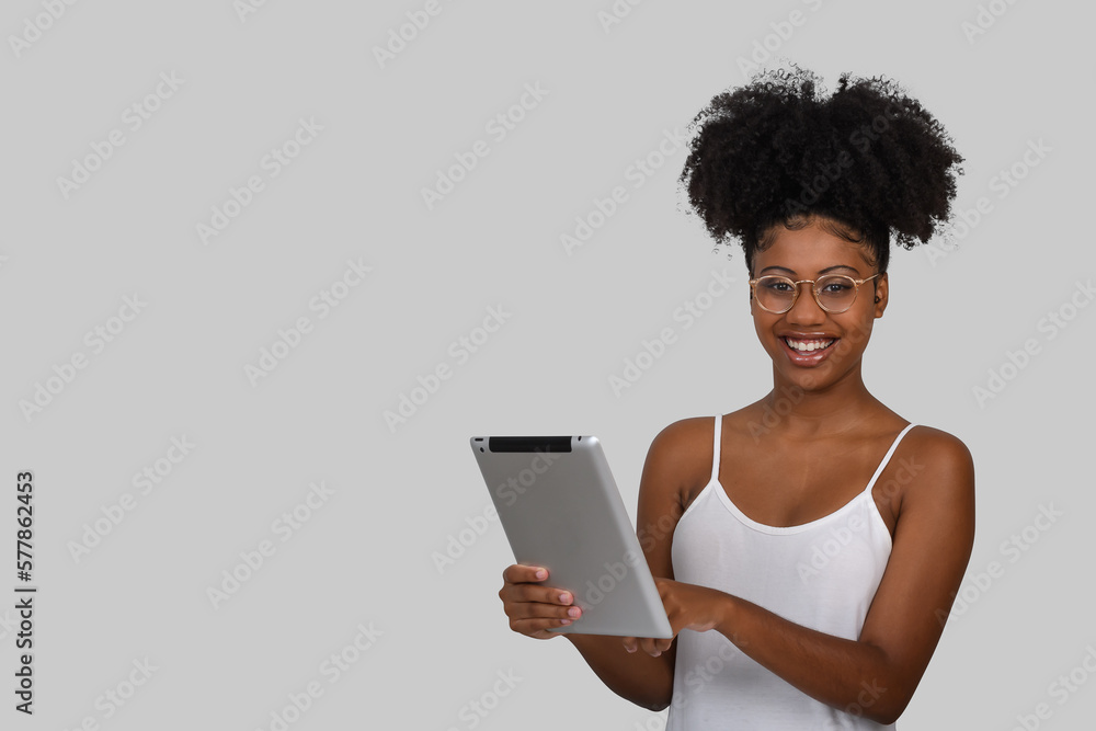 woman holding a tablet computer, wearing glasses looks at camera on gray background woman holding a tablet computer, wearing glasses looks at camera on gray background