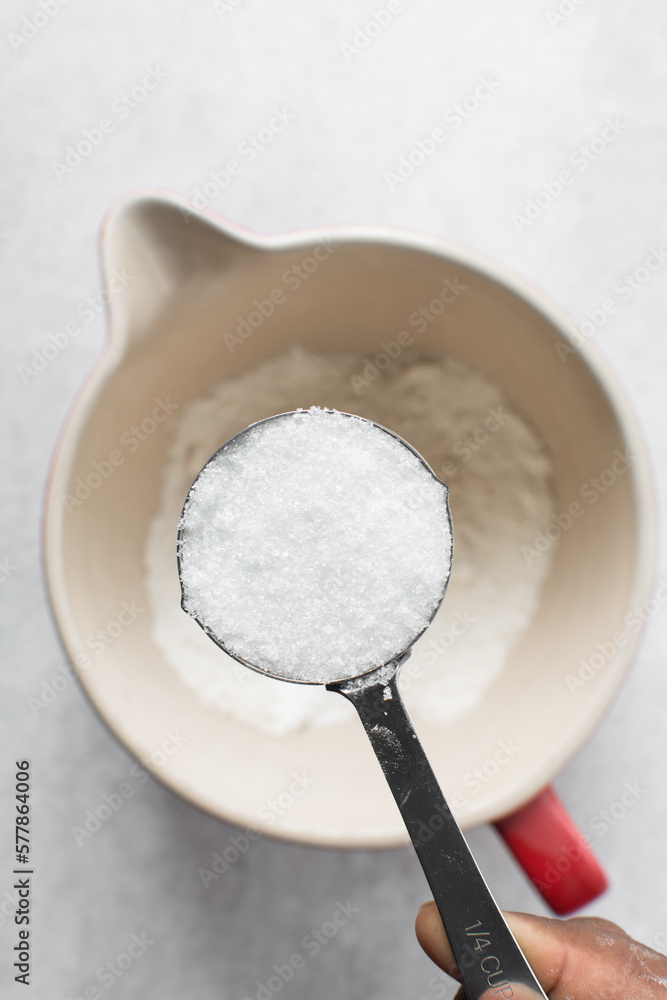 Top view of White sugar in a measuring cup, granulated sugar for baking, white sugar in a measuring cup