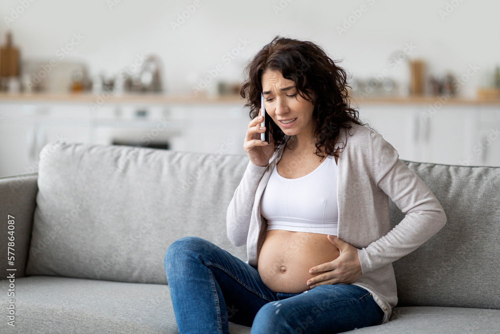 Pregnancy Cramps. Portrait Of Worried Pregnant Woman Touching Belly And Calling Emergency Pregnancy Cramps. Portrait Of Worried Pregnant Woman Touching Belly And Calling Emergency