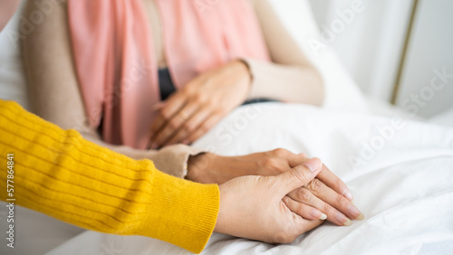 Close up Asian woman and friends sitting on bed two people holding hands. trusted friend, true friendship concept.