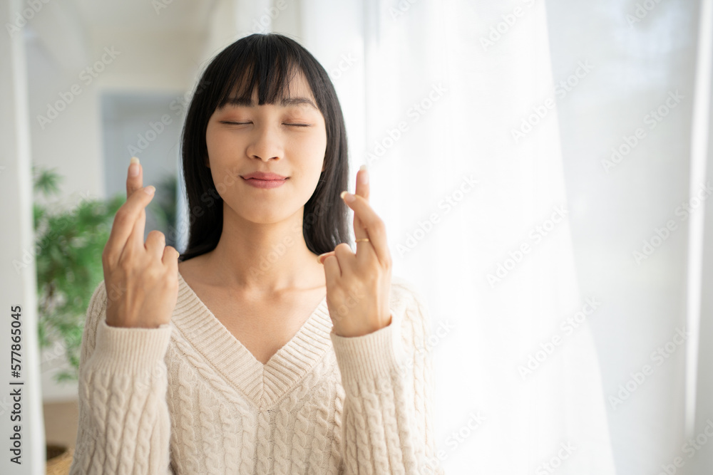 Pleased attractive Asian woman makes wish to win, raises hands with crossed fingers waits for gift results closes her eyes. Pleased attractive Asian woman makes wish to win, raises hands with crossed fingers waits for gift results closes her eyes.