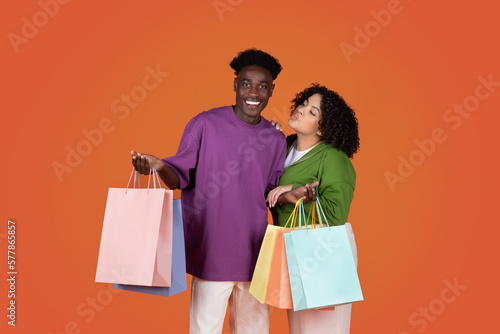 Happy multiracial young couple holding shopping bags