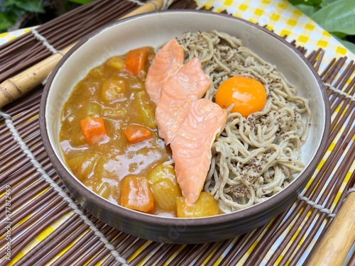 Salmon spinach nooddle with curry sauce and yolk on top photo