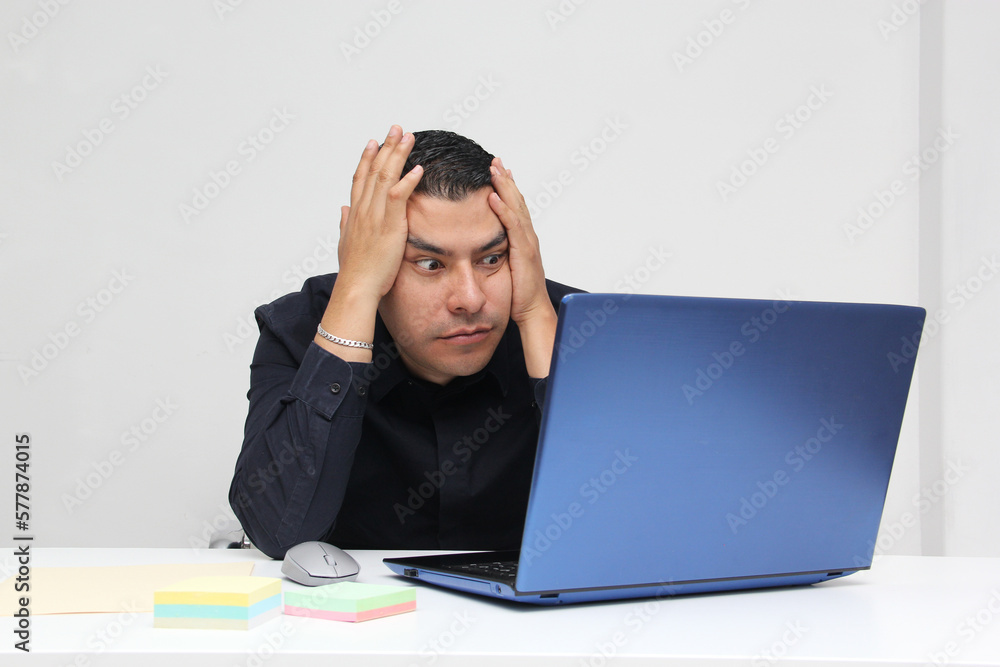 Latino adult man works from his room with his laptop due to overwork, suffers from stress, despair, anger, physical and metal exhaustion, burnout, headache Latino adult man works from his room with his laptop due to overwork, suffers from stress, despair, anger, physical and metal exhaustion, burnout, headache