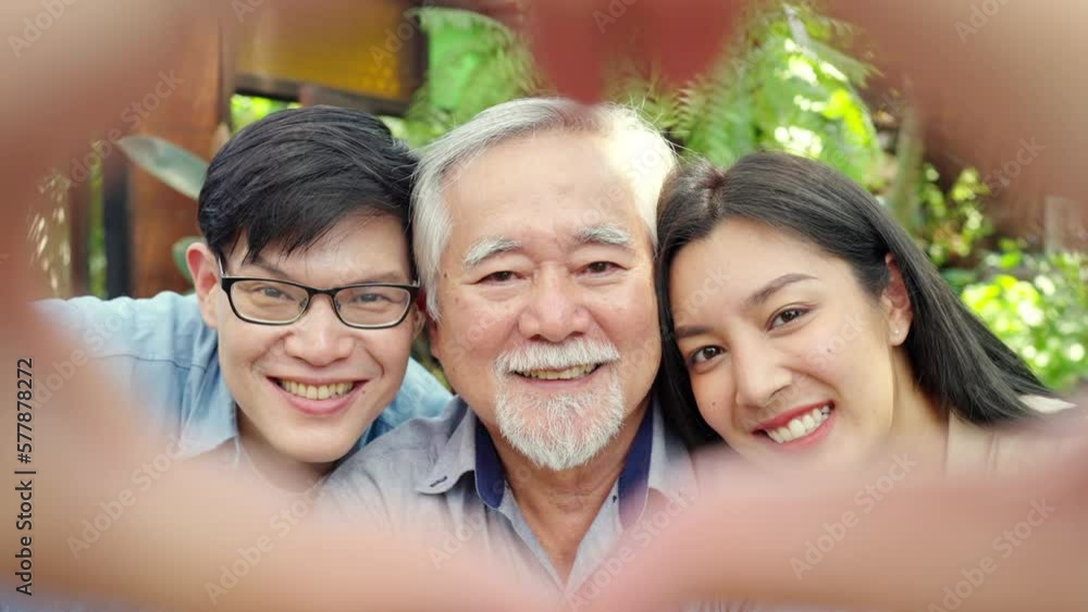 Happy Asian couple using mobile phone taking selfie with elderly father during having lunch eating food together at restaurant on summer vacation. Family relationship older people health care concept. Happy Asian couple using mobile phone taking selfie with elderly father during having lunch eating food together at restaurant on summer vacation. Family relationship older people health care concept.