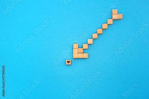 小さいハートマークのウッドキューブを矢の形をしたウッドキューブで指す青い背景
 photo