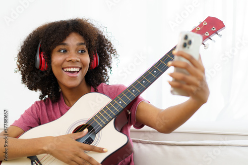 Print op canvas Happy cheerful African - American black woman playing in living room and making a live video or steaming on social media by using smartphone