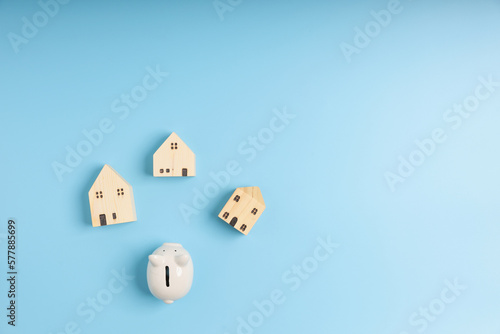 Top view  flat lay a white piggy bank and little wooden houses on a blue background with copy space. Save money  investment  finance  and loan concept.