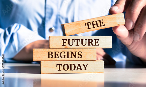 Close up on businessman holding a wooden block with "The future begins today" message