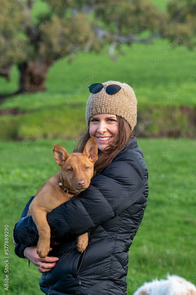 girl on a farm holding a puppy dog in her arms, tan kelpie puppy girl on a farm holding a puppy dog in her arms, tan kelpie puppy