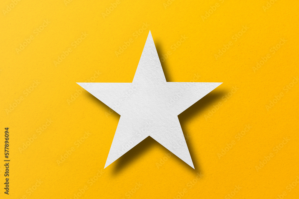 paper cut star shape with light and shadow placed on a yellow paper background paper cut star shape with light and shadow placed on a yellow paper background