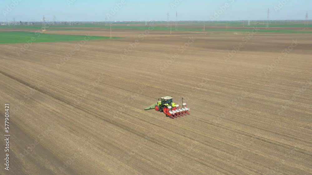 Above view, of tractor as pulling mechanical seeder machine over arable field, soil, planting new cereal crop, corn, maize. Above view, of tractor as pulling mechanical seeder machine over arable field, soil, planting new cereal crop, corn, maize.