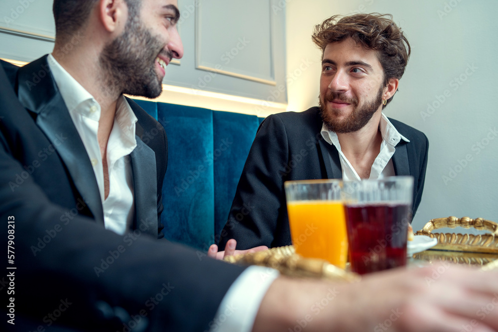 Young men enjoying breakfast and conversation in a restaurant - Breakfast and conversation at a cafe Young men enjoying breakfast and conversation in a restaurant - Breakfast and conversation at a cafe