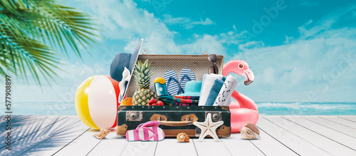 Suitcase with summer accessories at the tropical beach