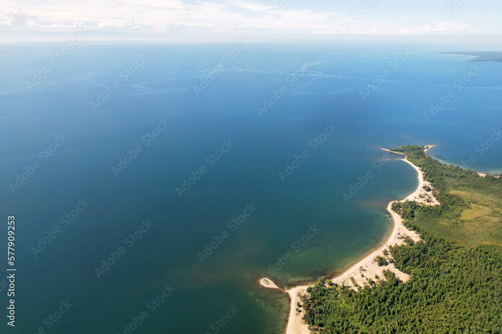 Beautiful summer seascape from the air. Sandy beach, rugged coastline, forest near the water.