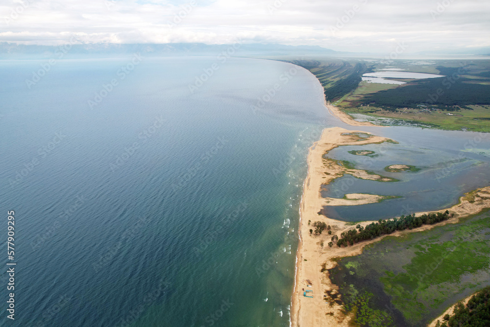 Barguzinsky Bay of Lake Baikal from the air. Waves on the lake, wildlife, the mouth of the Barguzin River. The Republic of Buryatia.