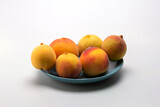 Fruits of ripe peaches on a dessert plate on a light background, close-up.