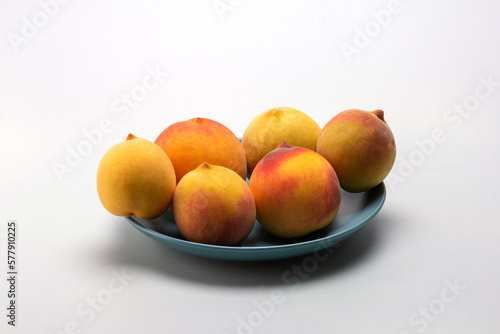 Fruits of ripe peaches on a dessert plate on a light background, close-up.