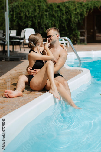 guy and a girl in bathing suits are relaxing  near the blue pool