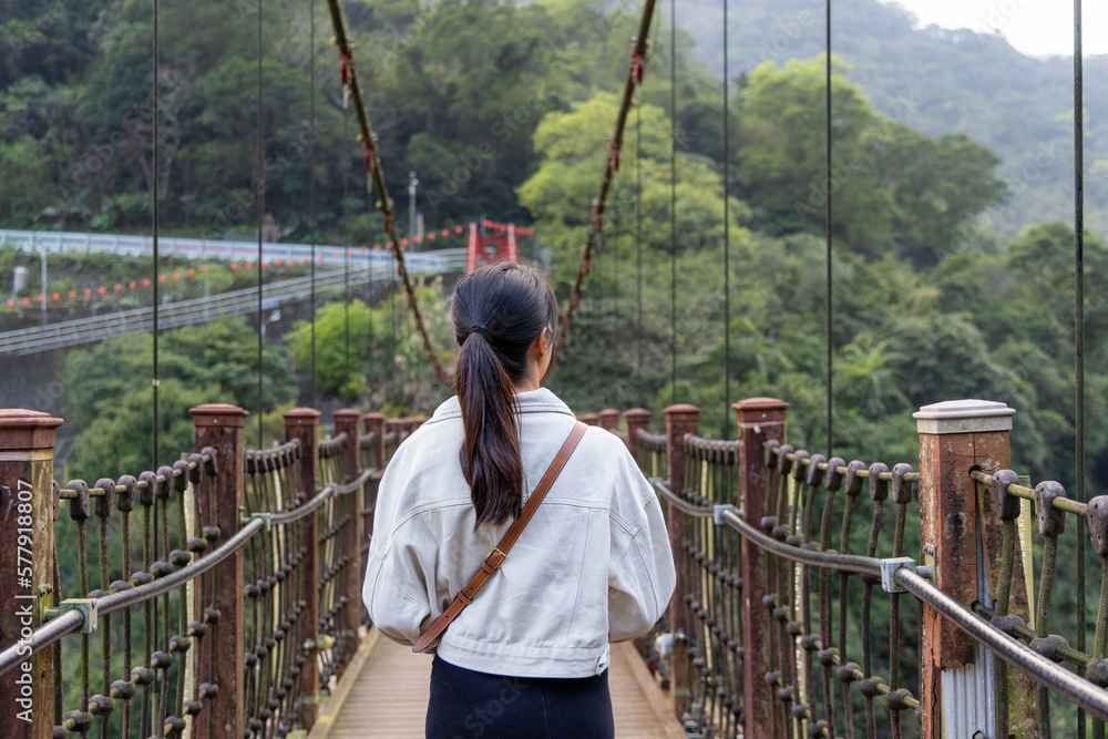 Woman crossing the suspension bridge in wulai of Taiwan Woman crossing the suspension bridge in wulai of Taiwan