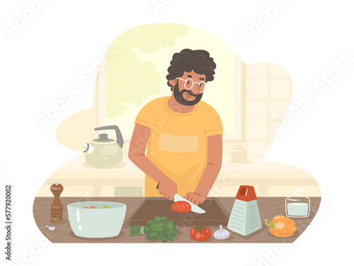 Hispanic man preparing dinner in the kitchen at home. The cook cuts vegetables to prepare a salad