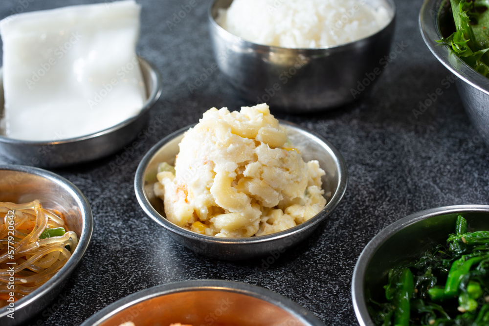 A view of several banchan side dishes, featuring macaroni salad. A view of several banchan side dishes, featuring macaroni salad.