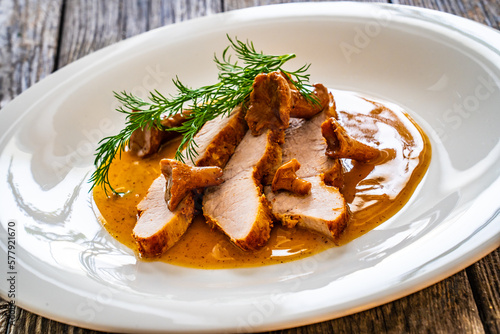 Fried veal loin in chanterelle mushrooms sauce on wooden table 