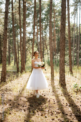 young bride in a white short dress in a spring pine forest © omelnickiy