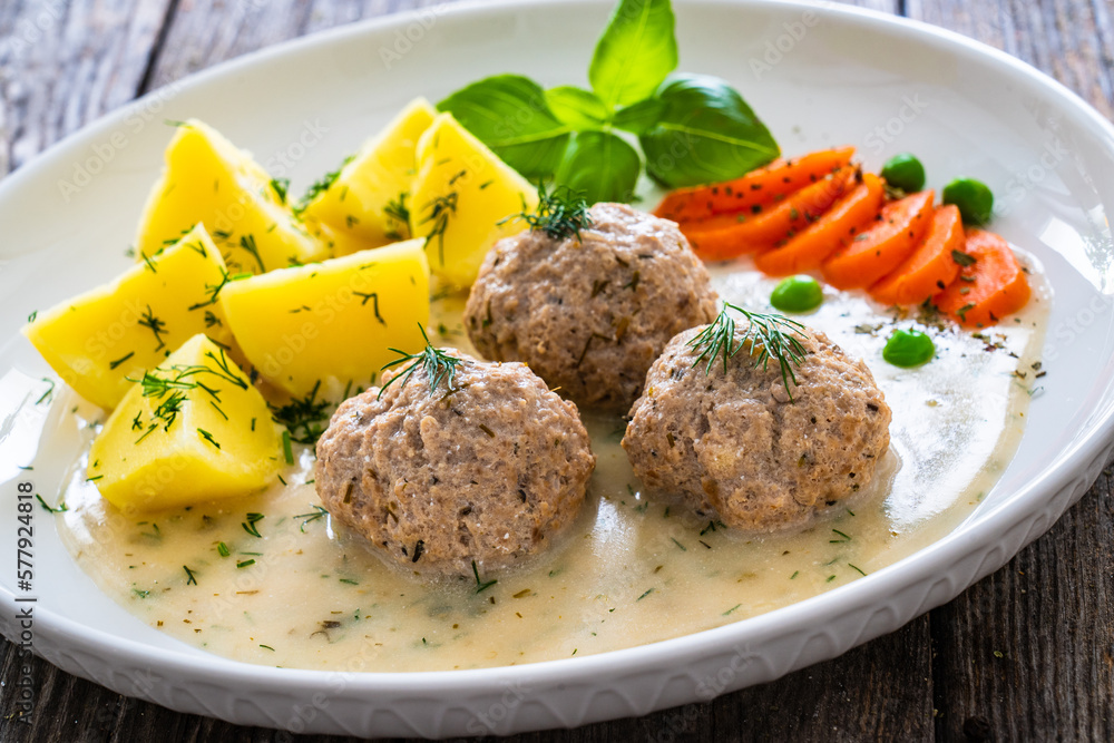 Boiled meatballs in dill sauce with potato puree, carrots and peas on wooden table
Boiled meatballs in dill sauce with potato puree, carrots and peas on wooden table