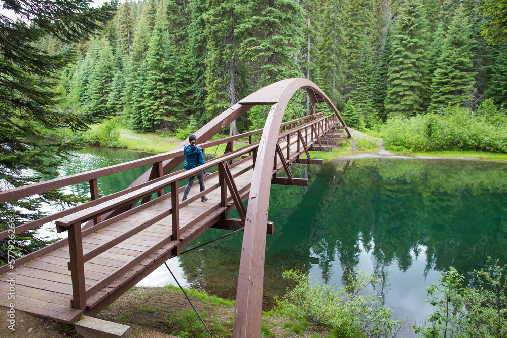 Female hiker crosses Rainbow Bridge at Lightning Lake, B.C. Female hiker crosses Rainbow Bridge at Lightning Lake, B.C.