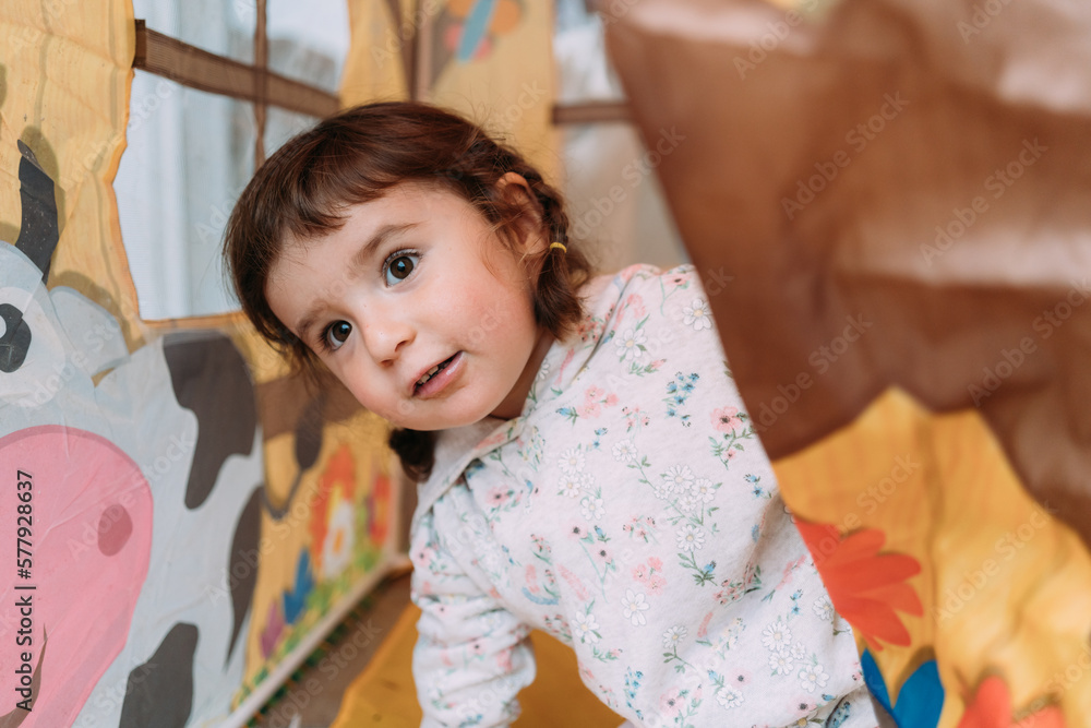 Happy toddler girl playing inside a toy house for kids Happy toddler girl playing inside a toy house for kids