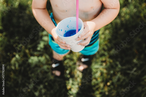 Above perspective of young boy drinkning blue snowcone photo