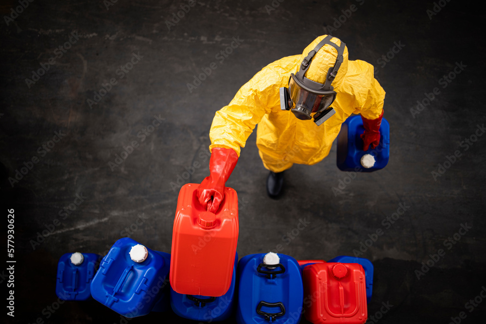 Obraz premium Professional worker in hazmat protection suit and gas mask working with dangerous chemicals inside factory.