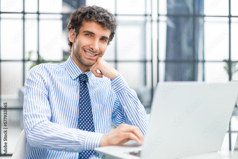 Young modern business man working using computer while sitting in the office. Young modern business man working using computer while sitting in the office.