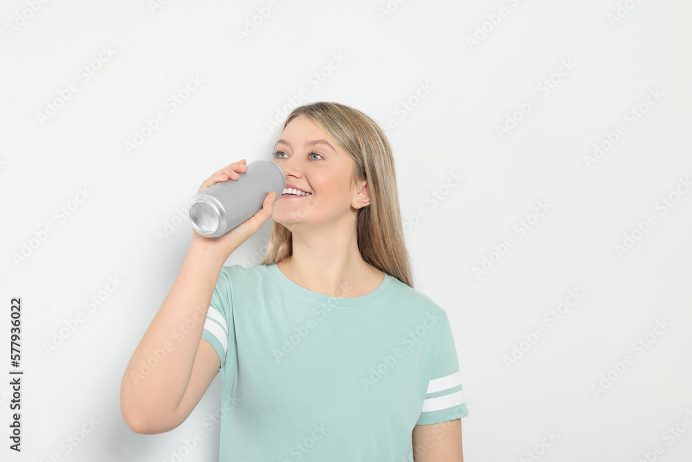 Beautiful woman drinking from beverage can on light background Beautiful woman drinking from beverage can on light background