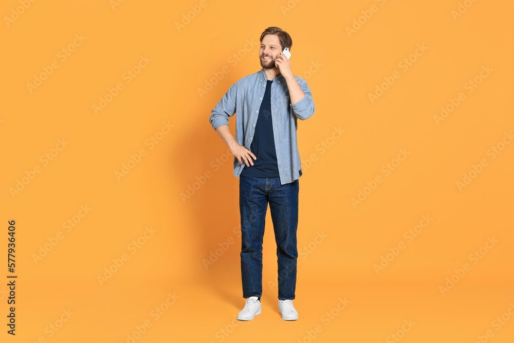 Man talking on smartphone against orange background Man talking on smartphone against orange background