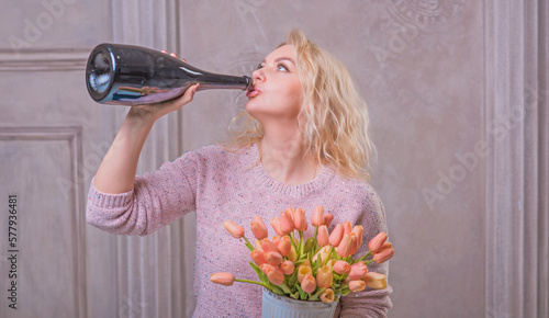 Nice happy woman celebrate with bottle of Champaign and flowers. Happy mood photo