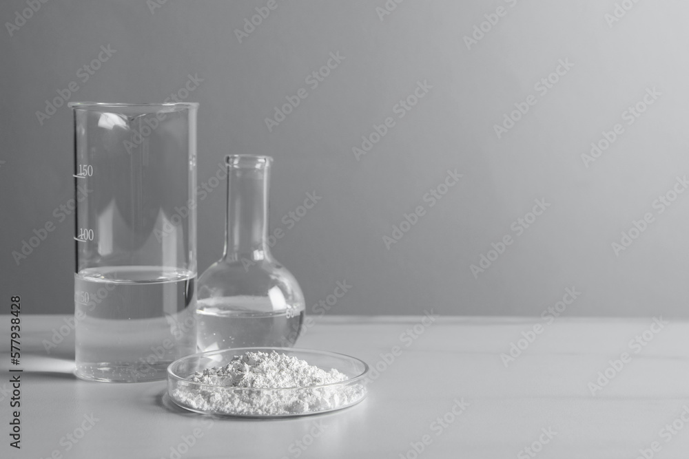 Petri dish with calcium carbonate powder and laboratory glassware on white table. Space for text - obrazy, fototapety, plakaty 