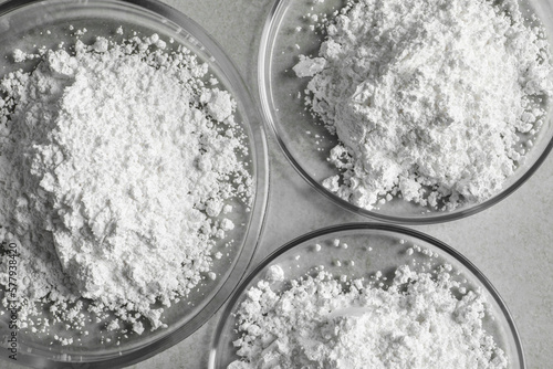 Petri dishes with calcium carbonate powder on light grey table, flat lay