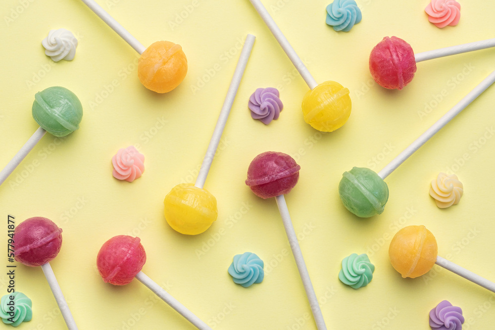 Sweet lollipops and candies on yellow background