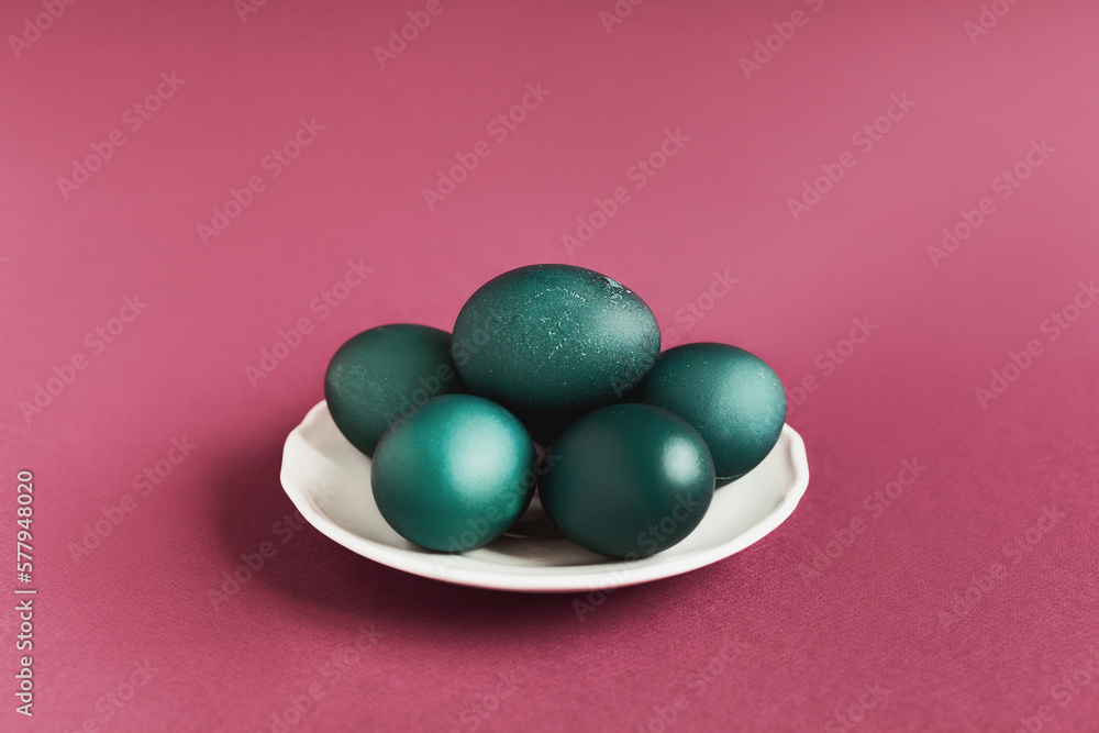 green color Easter eggs in white cup on wine red background