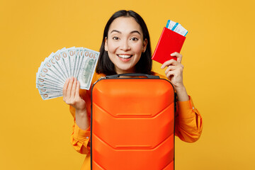 Young woman wear summer clothes hold passport ticket bag fan of cash money isolated on plain yellow background. Tourist travel abroad in free spare time rest getaway. Air flight trip journey concept.