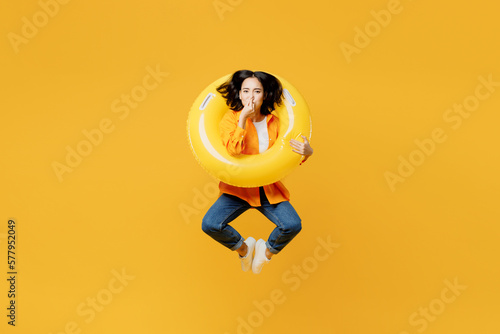 Bild auf Leinwand Young woman wear summer casual clothes jump in pool rubber ring close nose isolated on plain yellow background