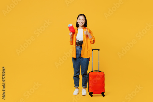 Young woman wears summer casual clothes hold passport ticket suitcase bag isolated on plain yellow background. Tourist travel abroad in free spare time rest getaway. Air flight trip journey concept.