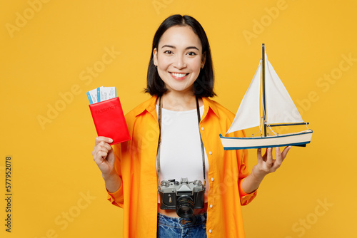 Young fun woman wear summer casual clothes hold passport ticket ship mockup isolated on plain yellow background. Tourist travel abroad in free spare time rest getaway. Air flight trip journey concept. #577952078