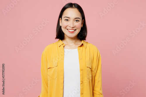 Fotografia Young smiling happy fun cool cheerful student woman of Asian ethnicity wear yellow shirt white t-shirt looking camera isolated on plain pastel light pink background studio portrait