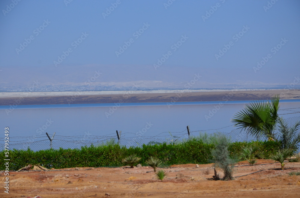 Panoramic view of the beautiful, clear blue Dead Sea shimmering and shining on a bright sunny day in Jordan and the dry land around it. Panoramic view of the beautiful, clear blue Dead Sea shimmering and shining on a bright sunny day in Jordan and the dry land around it.