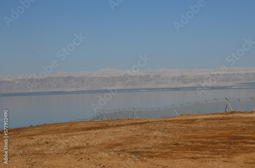 Panoramic view of the beautiful  clear blue Dead Sea shimmering and shining on a bright sunny day in Jordan and the dry land around it.